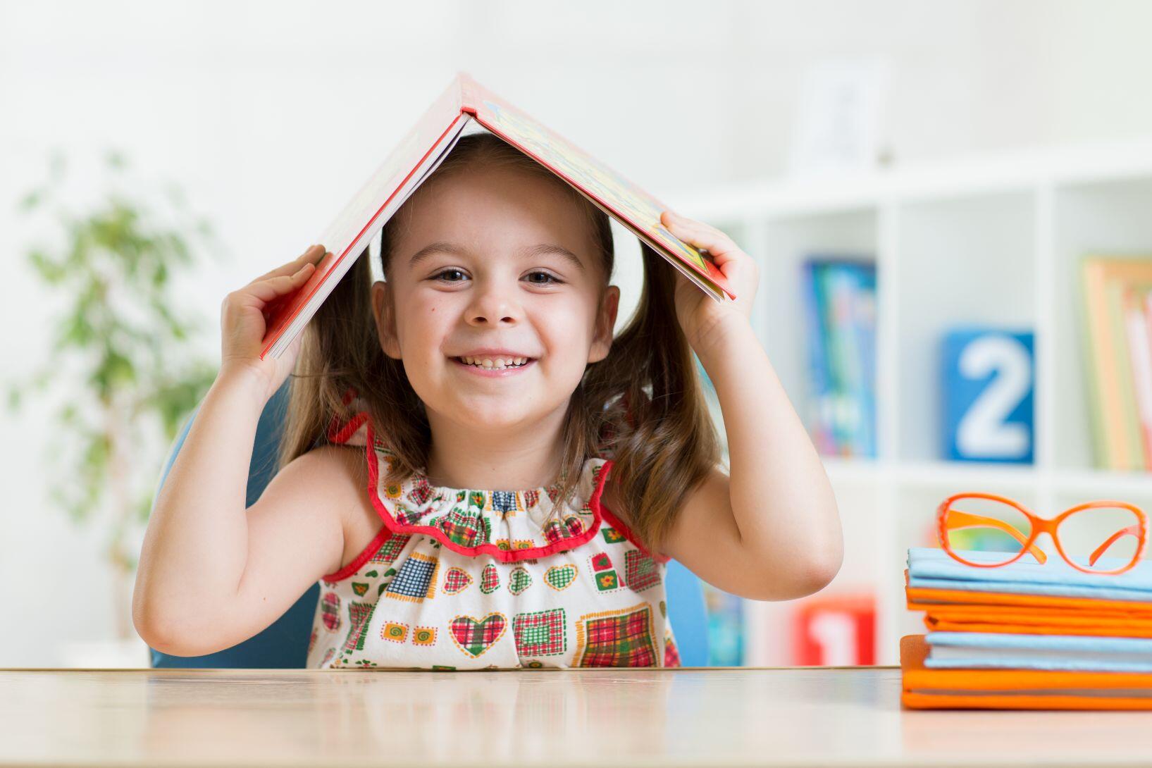After School 6 preschooler child girl with book over her head at www.staging.tidyreport.com
